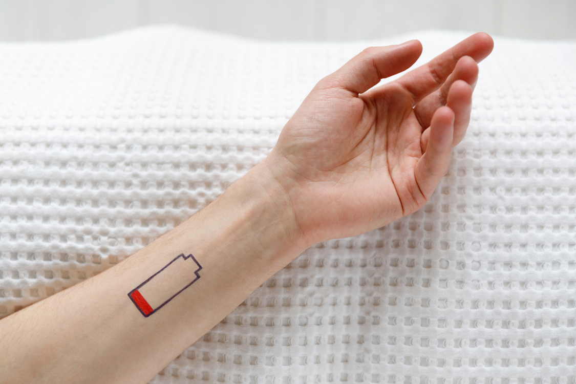 An arm on a white background with a low battery tattoo, symbolizing fatigue in autoimmune diseases
