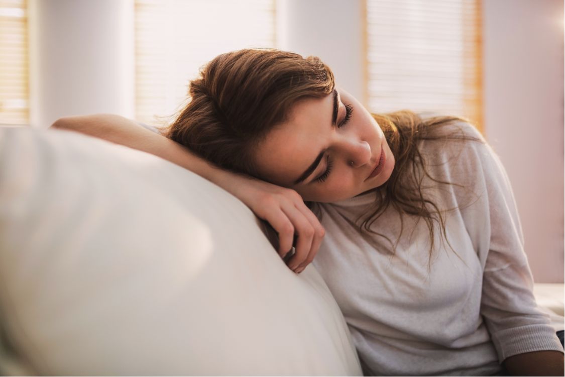 Tired perimenopausal woman experiencing fatigue on a white couch