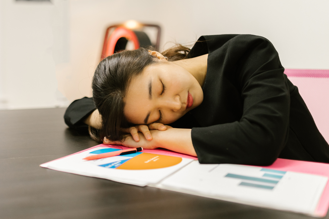 young woman tired at work with her head on the desk in the middle of her paperwork