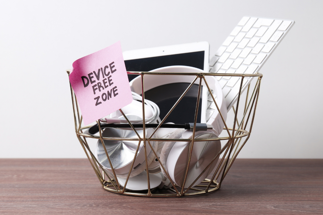 gold basket with a label 'device free zone' containing lots of digital devices