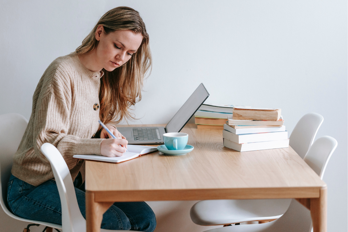 woman sat at desk focusing on her work with a pile of books